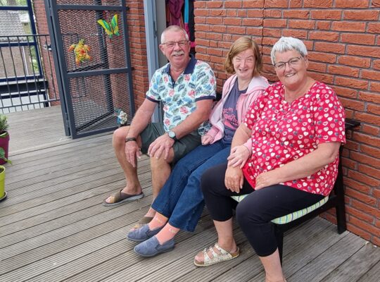 Drie mensen zitten samen op een bank